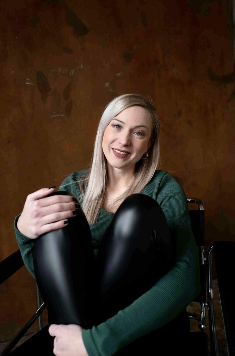 Aline mit angezogenen Beinen auf Swing Chair vor Rostwand